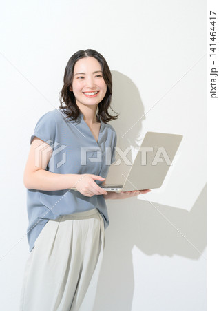 白背景でノートパソコンを持って微笑む日本人女性 141464417