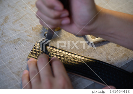 革ベルトにヘリ落とし加工をする職人の手元 革ベルトにヘリ落とし加工をする職人の手元 141464418