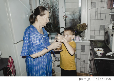grandmother in blue dress her grandson striped shirt share warm cup tea cozy kitchen table quiet smiles capturing gentle bond family comfort home simple joy spending time together over familiar ritual grandmother in blue dress her grandson striped shirt share warm cup tea cozy kitchen table quiet smiles capturing gentle bond family comfort home simple joy spending time together over familiar ritual 141464490