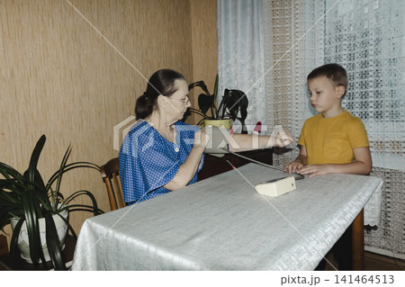 caring grandmother gently measures her grandsons blood pressure home monitor intimate domestic scene highlighting family support, health awareness quiet trust between generations warm familiar setting caring grandmother gently measures her grandsons blood pressure home monitor intimate domestic scene highlighting family support, health awareness quiet trust between generations warm familiar setting 141464513