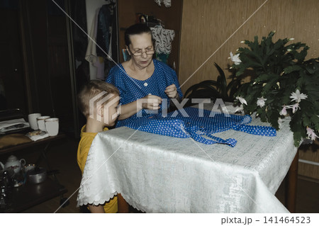 gentle grandmother blue top patiently shows her young grandson how sew piece fabric focused collaboration capturing warmth family learning passing traditions quiet joy creating something together gentle grandmother blue top patiently shows her young grandson how sew piece fabric focused collaboration capturing warmth family learning passing traditions quiet joy creating something together 141464523