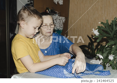 gentle grandmother blue top patiently shows her young grandson how sew piece fabric focused collaboration capturing warmth family learning passing traditions quiet joy creating something together gentle grandmother blue top patiently shows her young grandson how sew piece fabric focused collaboration capturing warmth family learning passing traditions quiet joy creating something together 141464525