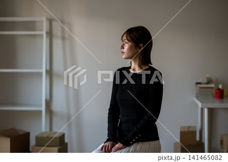 椅子に座り、窓の外を見る若い女性 141465082