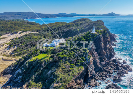 Aerial view of the historic Seal Rocks Lighthouse overlooking the rugged coastline, deep blue ocean and surrounding coastal landscape at Seal Rocks, NSW, Australia. 141465193