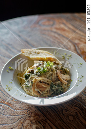 Creamy Mushroom Spaghetti with Spinach and Garlic Bread Served in White Bowl, Italian Restaurant Pasta Dish and Comfort Food on Rustic Wooden Table Creamy Mushroom Spaghetti with Spinach and Garlic Bread Served in White Bowl, Italian Restaurant Pasta Dish and Comfort Food on Rustic Wooden Table 141465806