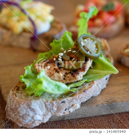 Gourmet chicken canape with jalapeno and fresh lettuce on artisan bread, close up of spicy appetizer finger food, catering snack and modern restaurant cuisine concept 141465940