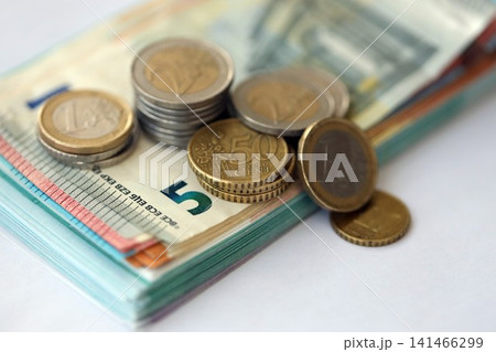Eurozone euro money bills and cent coins pile on table. Eurozone coins on banknotes of EUR currency Eurozone euro money bills and cent coins pile on table. Eurozone coins on banknotes of EUR currency 141466299
