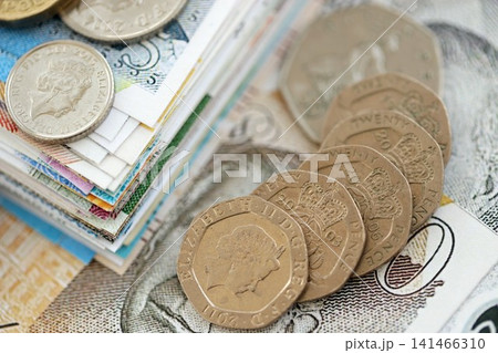 British pound money bills and penny coins pile. United Kingdom coins on banknotes of GBP currency 141466310