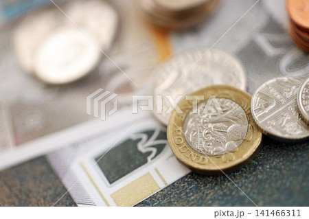British pound money bills and penny coins pile. United Kingdom coins on banknotes of GBP currency 141466311