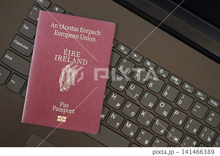 Ireland passport lies on black laptop keyboard buttons background . Technologies in Europe Ireland passport lies on black laptop keyboard buttons background . Technologies in Europe 141466389
