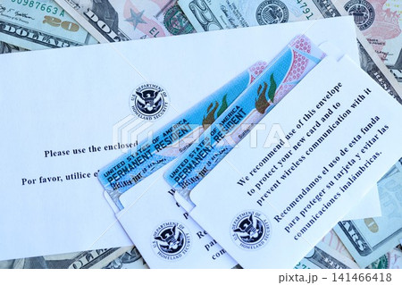 Permanent resident green cards and envelope lies on many dollar bills 141466418