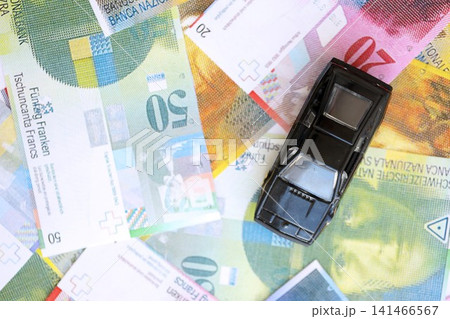 Swiss franc banknotes and toy car. The current francs money bills and black car lies on table Swiss franc banknotes and toy car. The current francs money bills and black car lies on table 141466567