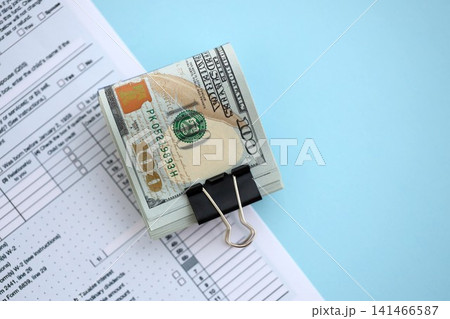 Big amount of United States USD dollar bills on table with 1040 tax return form Big amount of United States USD dollar bills on table with 1040 tax return form 141466587