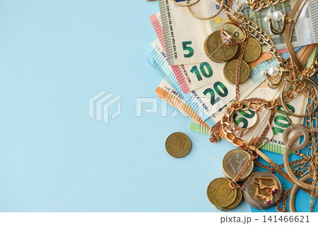 European union Euro money bills and coins with golden rings and jewelry necklaces on blue table European union Euro money bills and coins with golden rings and jewelry necklaces on blue table 141466621