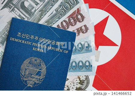 North Korean won money bills in big amount and passport lies on People Republic of Korea flag North Korean won money bills in big amount and passport lies on People Republic of Korea flag 141466652