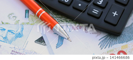 Argentine pesos money bills in big amount lies on table with pen and calculator close up Argentine pesos money bills in big amount lies on table with pen and calculator close up 141466686