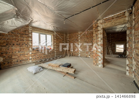 Interior of unfinished brick house with concrete floor and bare walls ready for plastering under construction. Real estate development Interior of unfinished brick house with concrete floor and bare walls ready for plastering under construction. Real estate development 141466898