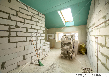 Interior of an apartment room with bare walls and ceiling under construction. Interior of an apartment room with bare walls and ceiling under construction. 141466899