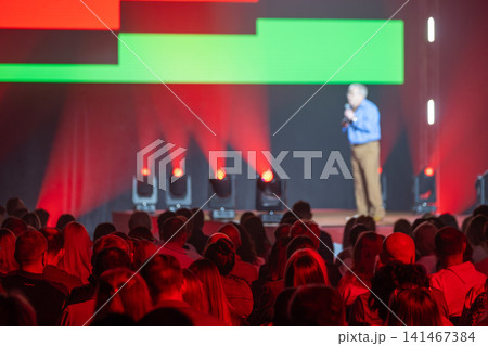 Speaker on stage with vibrant red and green lighting Speaker on stage with vibrant red and green lighting 141467384