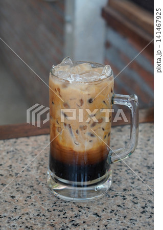 front view fresh cool and Iced black coffee with milk, served in a large handled glass mug and placed on a marble surface background, cool, food, drink, sweet, copy space front view fresh cool and Iced black coffee with milk, served in a large handled glass mug and placed on a marble surface background, cool, food, drink, sweet, copy space 141467925