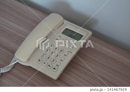 top view A white office phone on a wooden desk, white cement wall background, object, decor, technology, electric, copy space. top view A white office phone on a wooden desk, white cement wall background, object, decor, technology, electric, copy space. 141467929