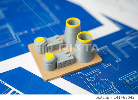 A nuclear power plant against a background of blue drawings and plans. Construction of new energy generating facilities and infrastructure. 141468042