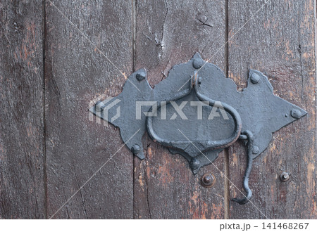 Antique wrought iron latch and handle on a weathered wooden door close up Antique wrought iron latch and handle on a weathered wooden door close up 141468267