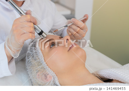 Injection-free mesotherapy or electroporation, beautician makes woman face therapy in clinic salon Injection-free mesotherapy or electroporation, beautician makes woman face therapy in clinic salon 141469455