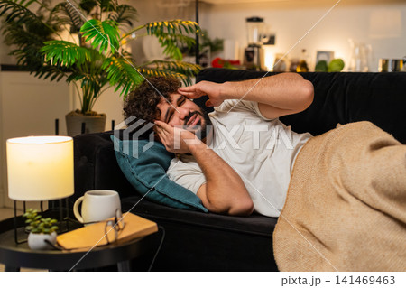 Arabian man lies with strong headache holds head at temple closes eyes feels pain needs rest tonight 141469463