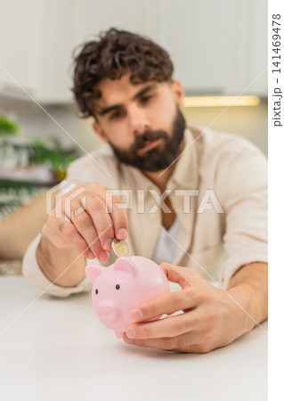 Indian man holding small piggy bank coin saving money dream about future personal savings big budget Indian man holding small piggy bank coin saving money dream about future personal savings big budget 141469478