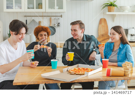 Home party. Overjoyed diverse friends eating ordered pizza for home party. Happy group multiracial young buddies enjoying spending free weekend time together having fun laughing joking communicating Home party. Overjoyed diverse friends eating ordered pizza for home party. Happy group multiracial young buddies enjoying spending free weekend time together having fun laughing joking communicating 141469717