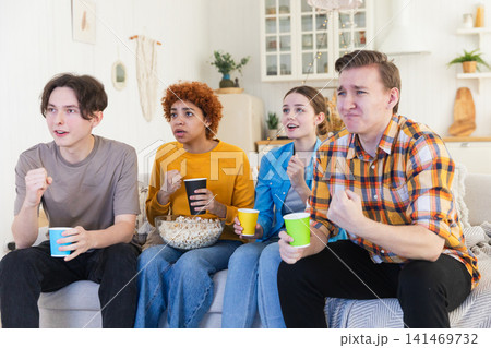 Group of friends watching sport match soccer football game on tv. Happy football fans celebrating victory at home. Friendship sports entertainment concept. Diverse buddies having fun together at home Group of friends watching sport match soccer football game on tv. Happy football fans celebrating victory at home. Friendship sports entertainment concept. Diverse buddies having fun together at home 141469732