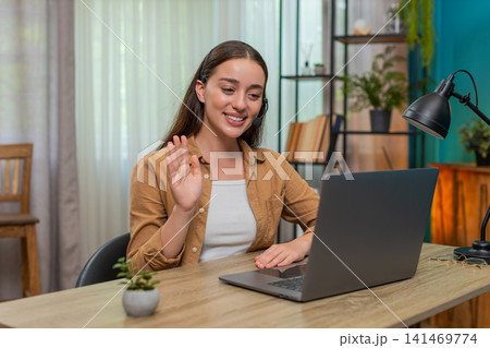 Young woman hosting online conference on laptop speaking in microphone with clear professional style Young woman hosting online conference on laptop speaking in microphone with clear professional style 141469774