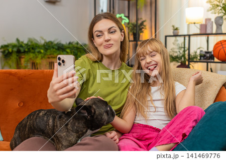 Mother daughter dog selfie joke with fun filter masks laugh together with smartphone playful family Mother daughter dog selfie joke with fun filter masks laugh together with smartphone playful family 141469776