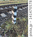 Striped Railway Marker Pole Stands Guard by Train Tracks 141470578