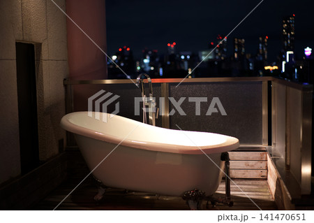 都会の夜景を見渡す高級ホテルのバルコニーと屋外猫脚バスタブ 都会の夜景を見渡す高級ホテルのバルコニーと屋外猫脚バスタブ 141470651