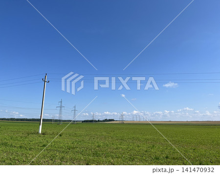 Electricity transmission lines across green farmland under blue sky with power grid Electricity transmission lines across green farmland under blue sky with power grid 141470932