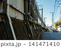 青空の下、日本の都市風景に広がるコンクリート壁と電線 141471410