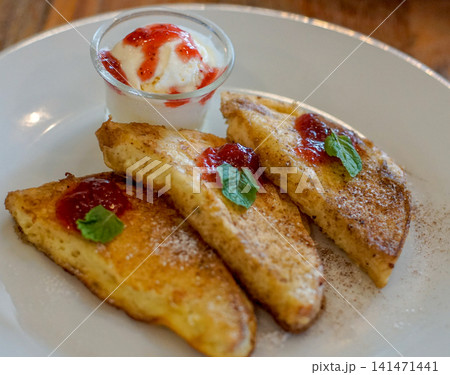 Golden French Toast with Strawberry Sauce, Vanilla Ice Cream, Powdered Sugar and Fresh Mint on a Plate, Sweet Breakfast or Brunch Dessert Golden French Toast with Strawberry Sauce, Vanilla Ice Cream, Powdered Sugar and Fresh Mint on a Plate, Sweet Breakfast or Brunch Dessert 141471441