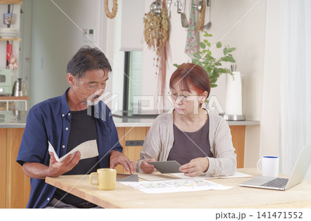 住宅の図面を見ながら話し合うシニア夫婦 住宅の図面を見ながら話し合うシニア夫婦 141471552