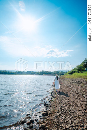 太陽と青空の下で湖畔を歩く女性 太陽と青空の下で湖畔を歩く女性 141471593