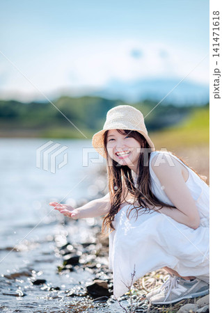 湖畔にしゃがみ微笑む麦わら帽子の女性 湖畔にしゃがみ微笑む麦わら帽子の女性 141471618