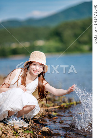 湖畔で水を弾いて遊ぶ白ワンピースの女性 湖畔で水を弾いて遊ぶ白ワンピースの女性 141471640