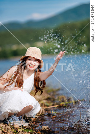 湖畔で手を広げて水遊びをする女性 湖畔で手を広げて水遊びをする女性 141471644