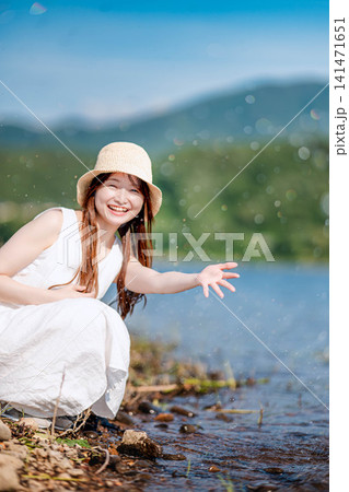 湖畔で水しぶきを上げて笑う麦わら帽子の女性 湖畔で水しぶきを上げて笑う麦わら帽子の女性 141471651