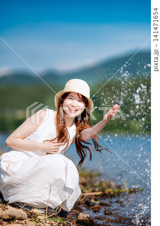 きらめく水辺で水しぶきを上げる麦わら帽子の女性 きらめく水辺で水しぶきを上げる麦わら帽子の女性 141471654