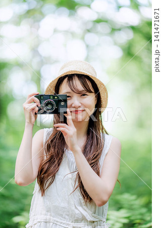 新緑を背景にフィルムカメラで撮影する帽子の女性 141471671