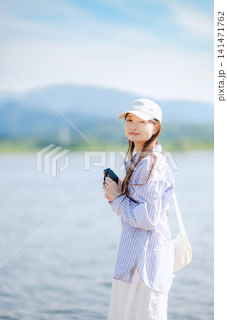 水辺でカメラを構える水色シャツの女性 水辺でカメラを構える水色シャツの女性 141471762