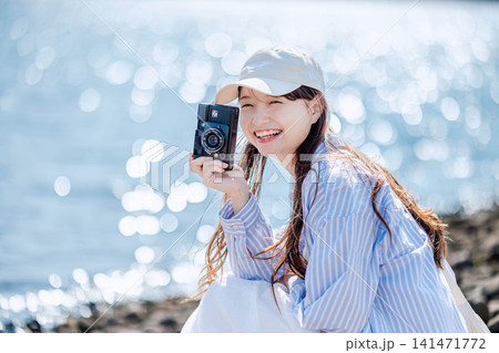 きらめく湖畔でカメラを構え微笑む女性 きらめく湖畔でカメラを構え微笑む女性 141471772