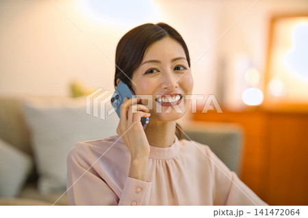 夜部屋でリラックスしてスマホを見る40代の女性 夜部屋でリラックスしてスマホを見る40代の女性 141472064